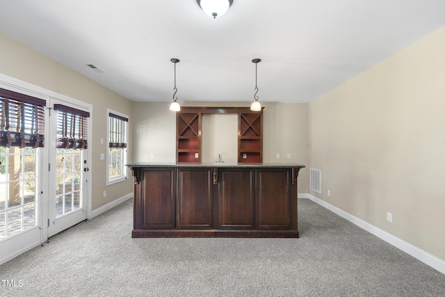 interior space featuring light carpet, baseboards, indoor wet bar, and decorative light fixtures