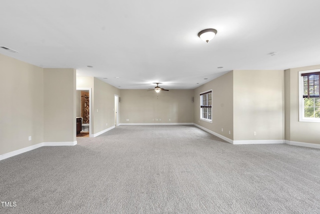 carpeted empty room featuring ceiling fan, visible vents, and baseboards