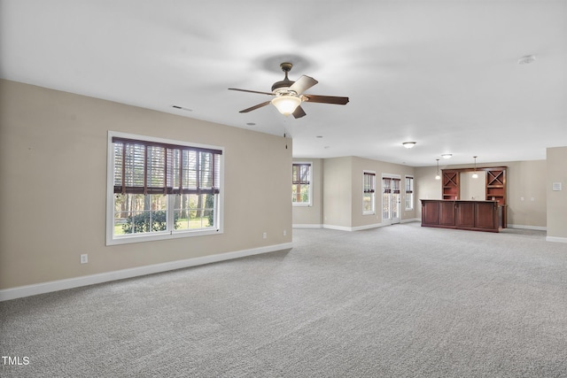 unfurnished living room with light carpet, a ceiling fan, visible vents, and baseboards