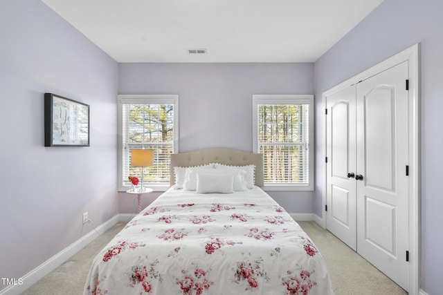 bedroom featuring a closet, visible vents, baseboards, and multiple windows