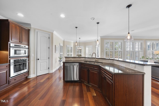 kitchen featuring dark wood-type flooring, a sink, appliances with stainless steel finishes, dark stone counters, and crown molding