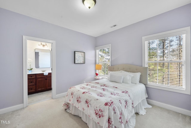 bedroom with light colored carpet, visible vents, baseboards, and ensuite bathroom