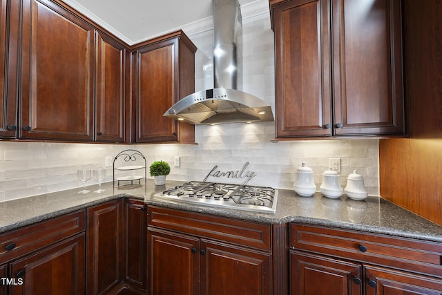 kitchen featuring stainless steel gas cooktop, wall chimney exhaust hood, dark stone counters, and backsplash