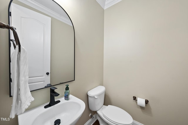 half bath featuring baseboards, a sink, toilet, and crown molding