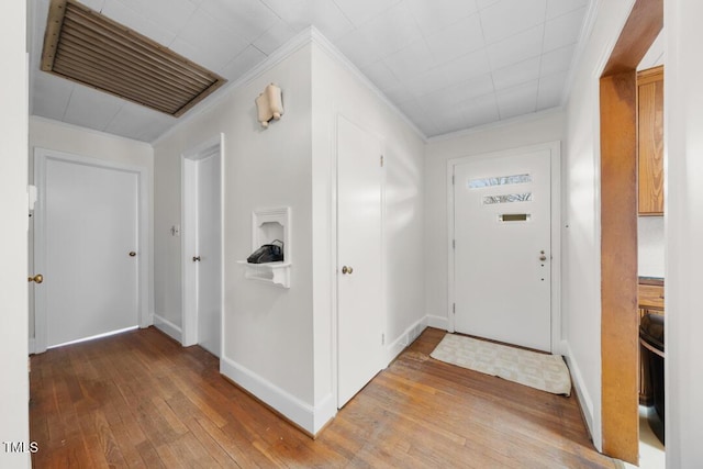 entryway featuring light wood-style floors, baseboards, visible vents, and ornamental molding