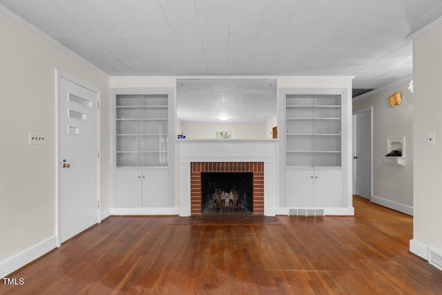 unfurnished living room featuring visible vents, wood-type flooring, crown molding, a brick fireplace, and built in shelves