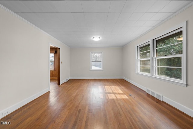 unfurnished room featuring baseboards, visible vents, wood finished floors, and ornamental molding