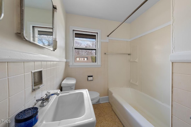 full bath featuring washtub / shower combination, a sink, toilet, and tile walls