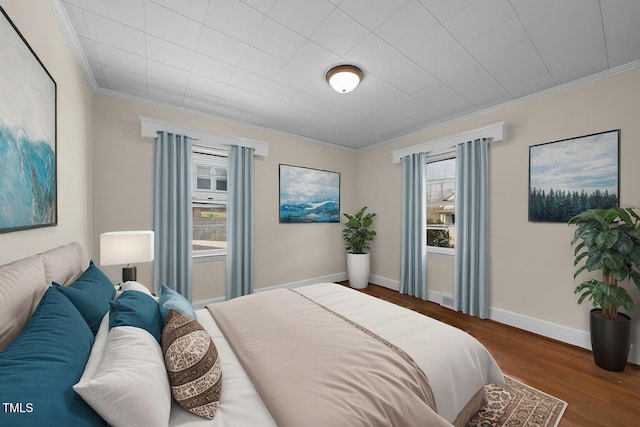 bedroom with baseboards, ornamental molding, and wood finished floors