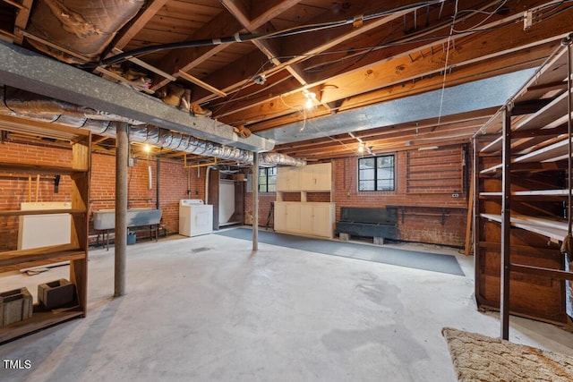 basement featuring brick wall and washer / clothes dryer