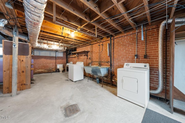 unfinished basement with washer / dryer, a sink, and brick wall