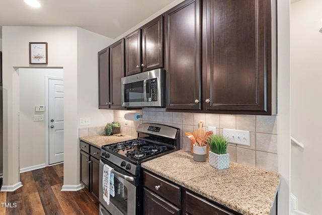 kitchen with appliances with stainless steel finishes, dark wood finished floors, dark brown cabinetry, and tasteful backsplash