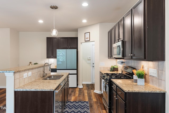 kitchen featuring dark wood finished floors, appliances with stainless steel finishes, a sink, and dark brown cabinetry