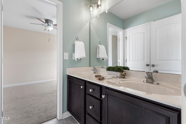 bathroom with ceiling fan, double vanity, a sink, and baseboards