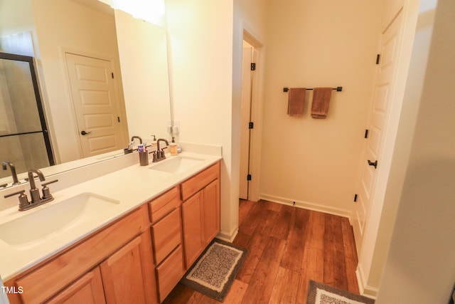 full bath with double vanity, visible vents, a sink, and wood finished floors