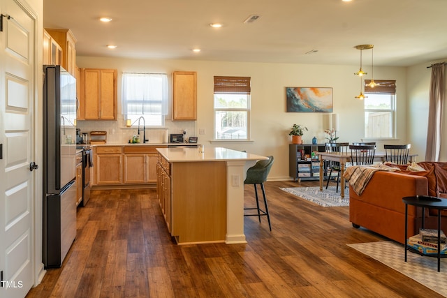 kitchen featuring a breakfast bar area, visible vents, light countertops, stainless steel refrigerator, and dark wood-style floors