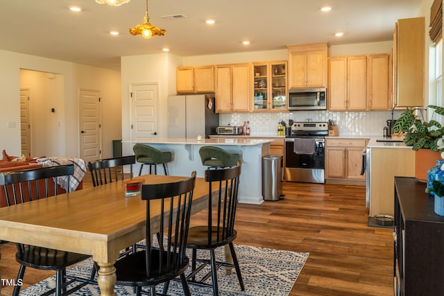 kitchen featuring dark wood-style flooring, visible vents, backsplash, appliances with stainless steel finishes, and light brown cabinets