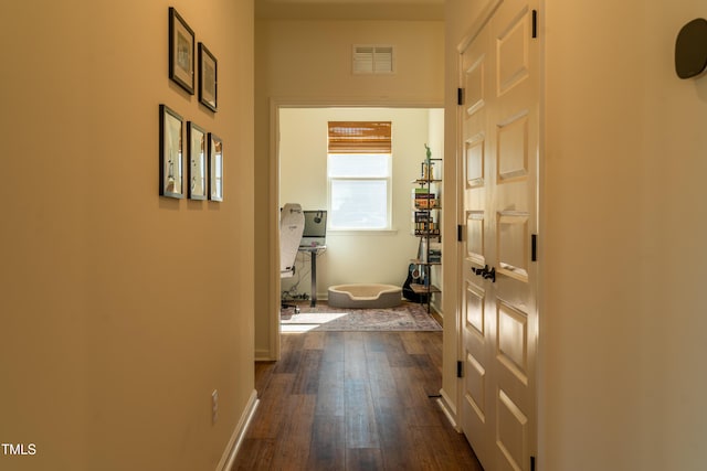 hallway featuring dark wood-style floors, visible vents, and baseboards