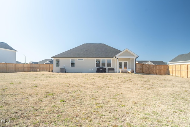 rear view of property featuring central air condition unit, a fenced backyard, and a yard