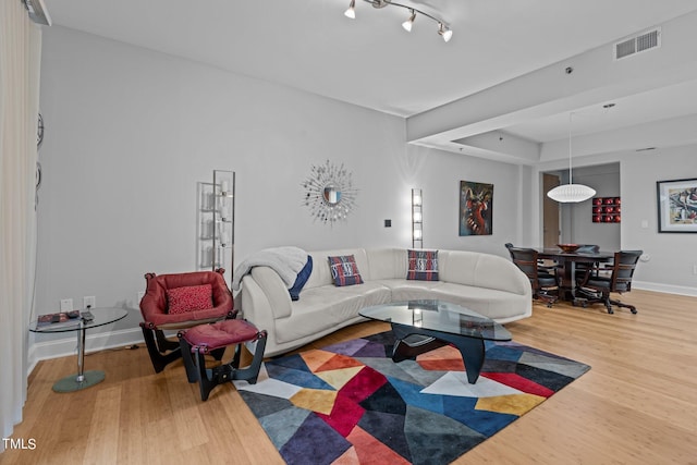 living room featuring visible vents, baseboards, and wood finished floors