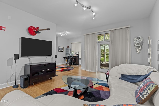 living area featuring track lighting, baseboards, and wood finished floors