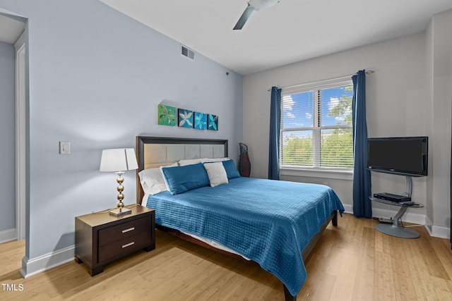 bedroom with light wood-style floors, visible vents, baseboards, and a ceiling fan