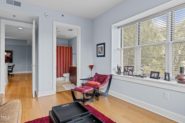 living area with visible vents, light wood-style flooring, and baseboards