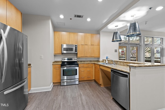 kitchen featuring a peninsula, a sink, visible vents, appliances with stainless steel finishes, and light stone countertops