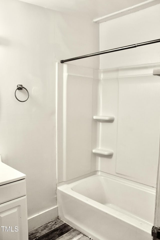 full bath with bathtub / shower combination, vanity, baseboards, and wood finished floors