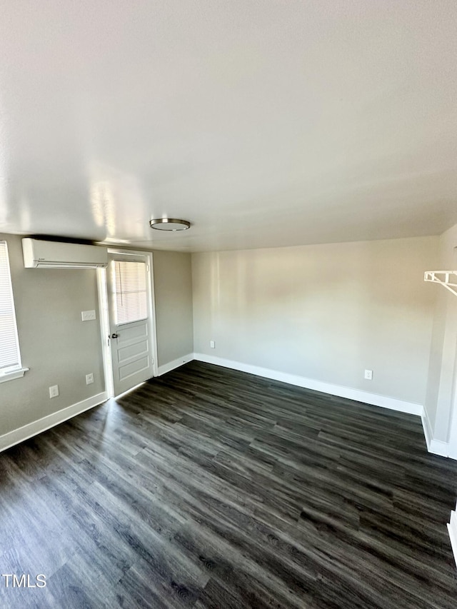 empty room with dark wood-type flooring, a wall mounted air conditioner, and baseboards