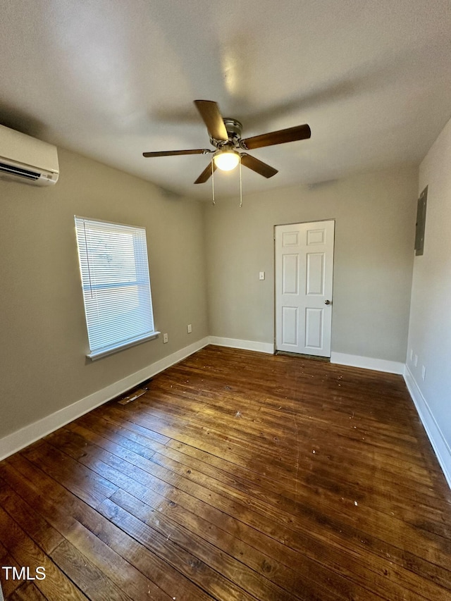 spare room with ceiling fan, wood-type flooring, baseboards, electric panel, and a wall mounted air conditioner