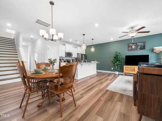 dining space featuring recessed lighting, visible vents, light wood-style flooring, stairs, and ceiling fan with notable chandelier