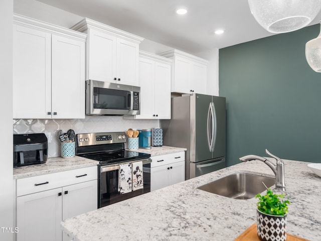 kitchen featuring stainless steel appliances, a sink, white cabinets, and decorative backsplash