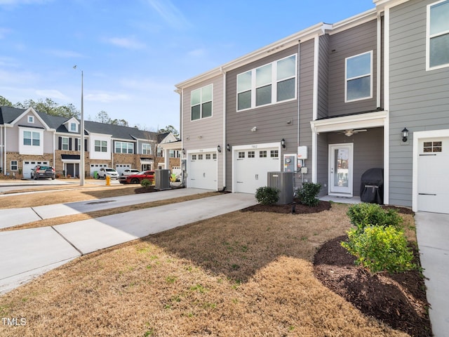 townhome / multi-family property with a residential view, concrete driveway, cooling unit, and an attached garage