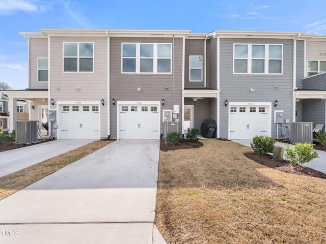 multi unit property featuring a garage, driveway, and central AC unit