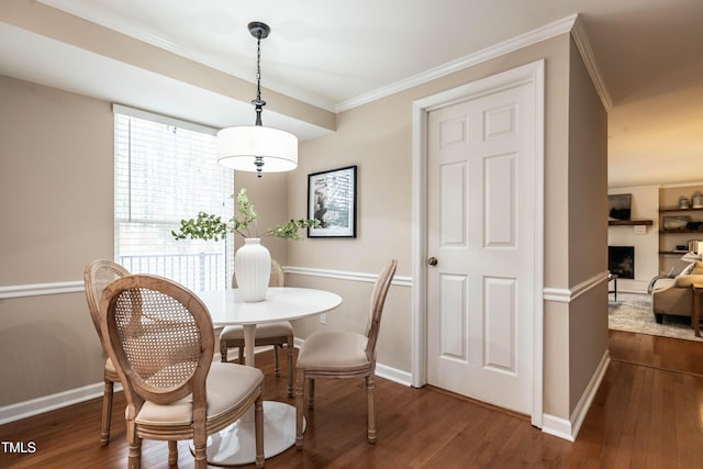 dining area with ornamental molding, dark wood-type flooring, and a fireplace