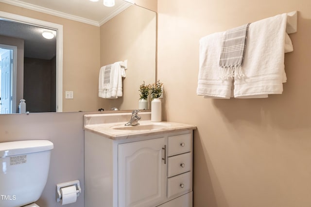 half bathroom with ornamental molding, vanity, and toilet