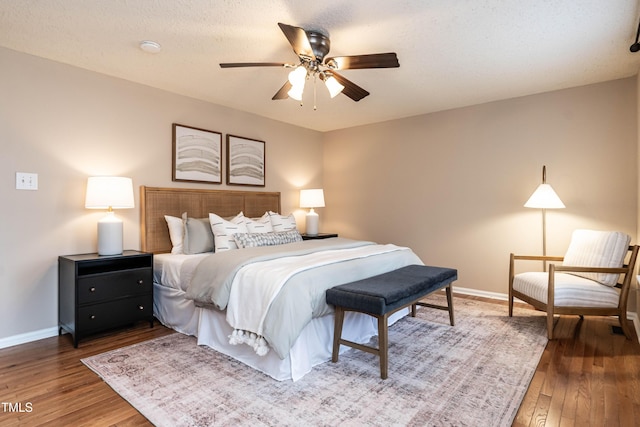 bedroom with a ceiling fan, a textured ceiling, baseboards, and hardwood / wood-style floors