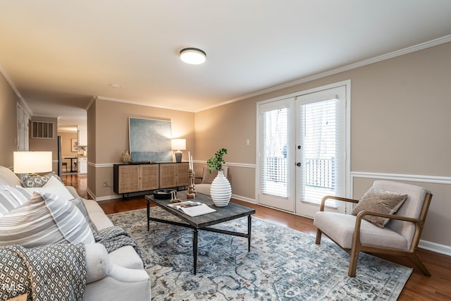 living room with french doors, crown molding, visible vents, wood finished floors, and baseboards