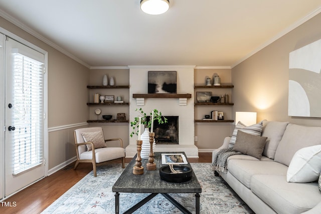 living area featuring ornamental molding, a brick fireplace, and wood finished floors