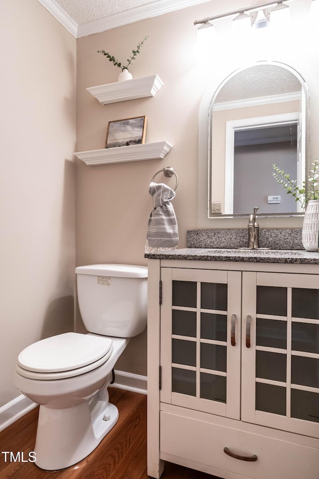 half bathroom featuring crown molding, a textured ceiling, toilet, and wood finished floors