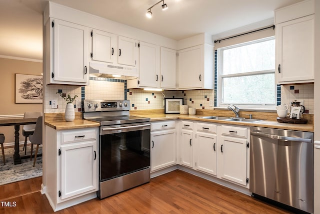 kitchen featuring dark wood-type flooring, stainless steel appliances, light countertops, under cabinet range hood, and a sink