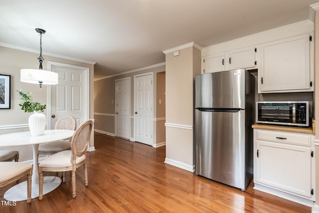 kitchen with light wood-style floors, white cabinetry, stainless steel appliances, and crown molding