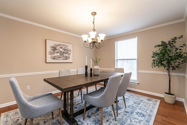 dining room with an inviting chandelier, baseboards, wood finished floors, and ornamental molding