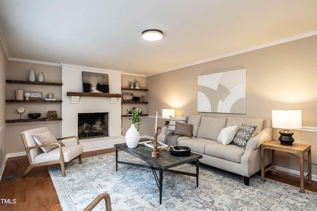 living room with a brick fireplace, baseboards, ornamental molding, and wood finished floors