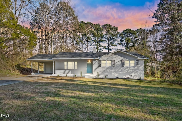 single story home featuring a lawn, a carport, and concrete driveway