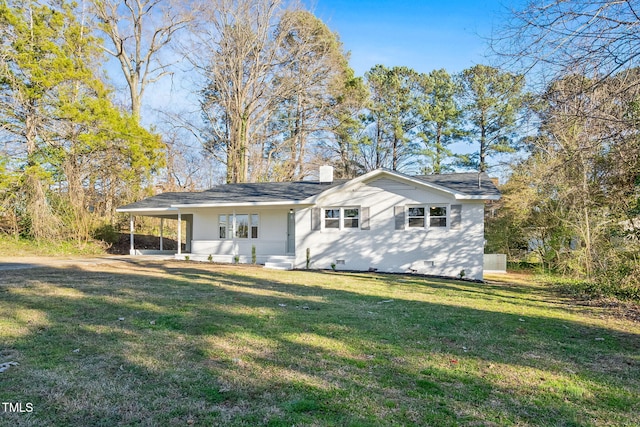 back of house featuring crawl space, a carport, a chimney, and a lawn