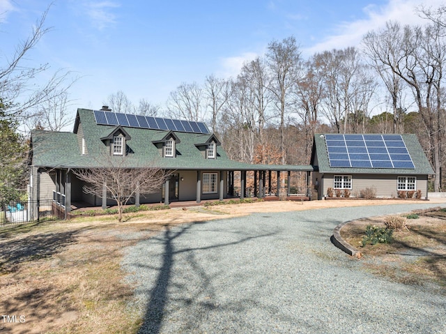 view of front of home with covered porch, solar panels, and driveway