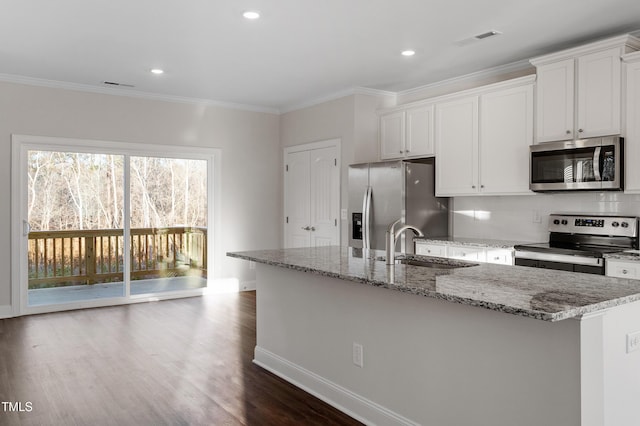 kitchen with a sink, visible vents, ornamental molding, appliances with stainless steel finishes, and an island with sink