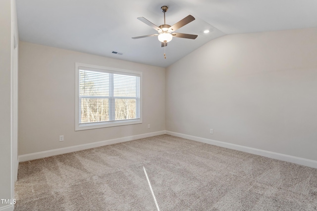 carpeted empty room featuring lofted ceiling, ceiling fan, visible vents, and baseboards